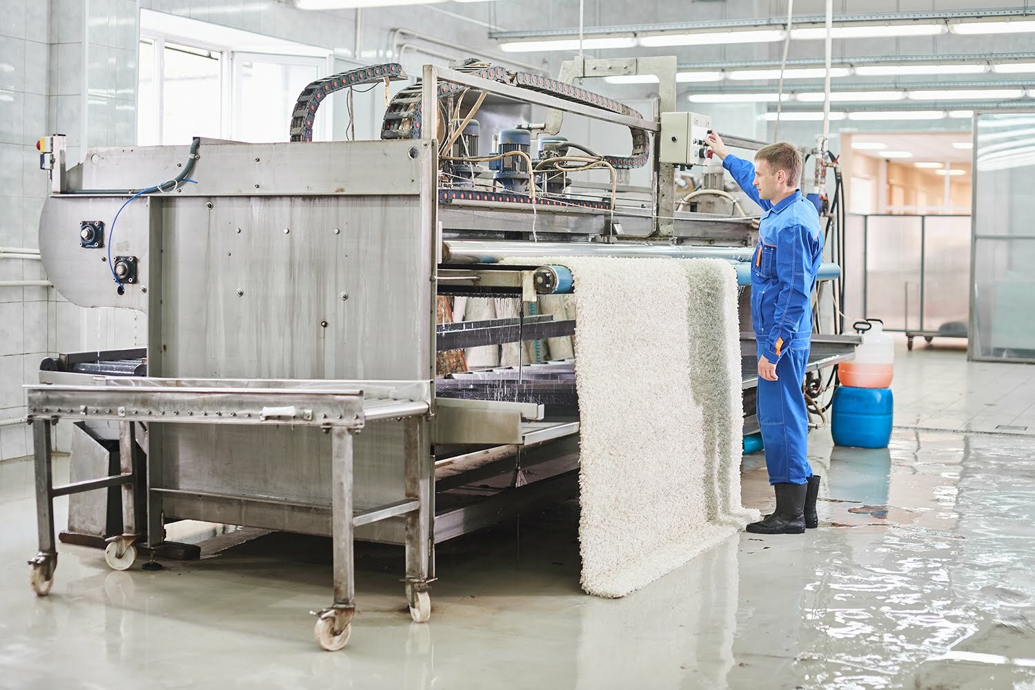 Laundry worker in the process of working on automatic machine for carpet washing in dry cleaning