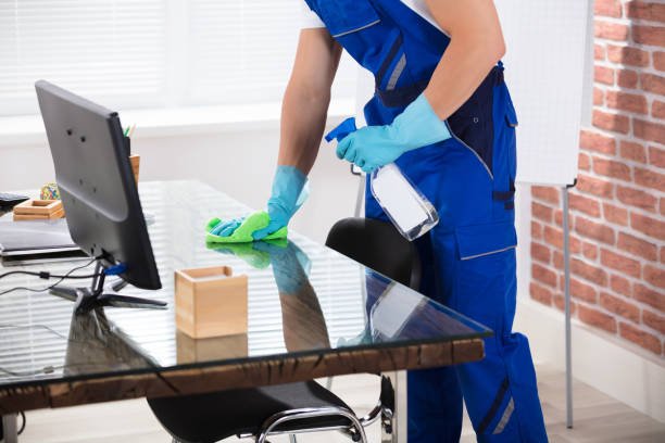 Close-up Of A Male Janitor Cleaning Desk With Cloth In Office
