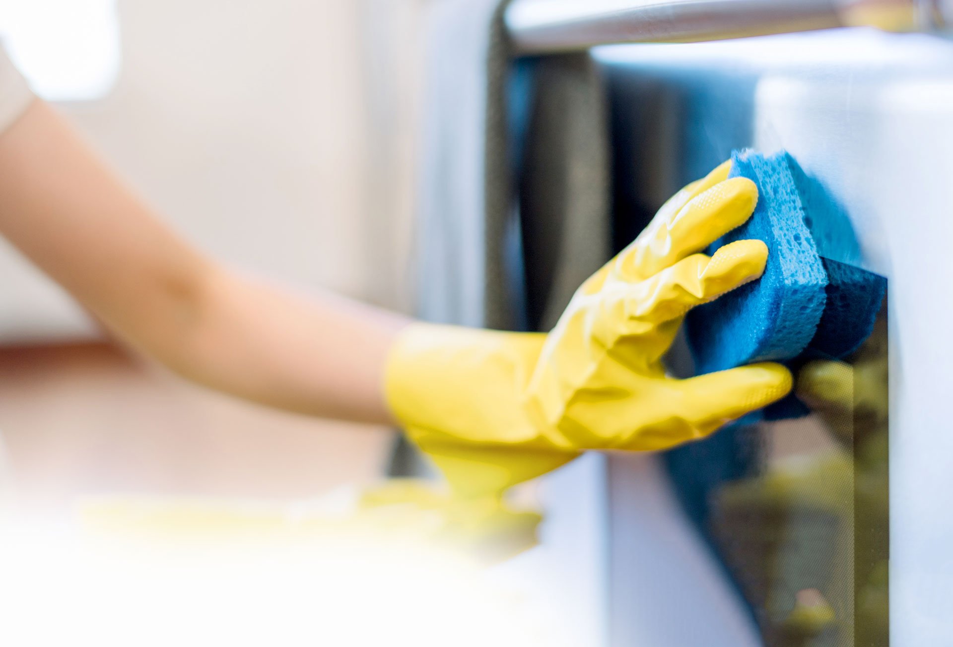 Hand In A Yellow Glove Cleaning Kitchen Appliances